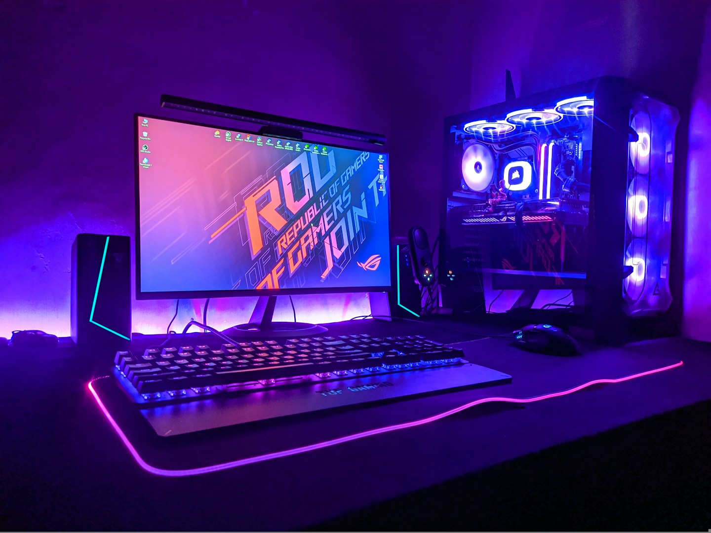 Gamer's glowing desktop computer and peripherals on a desk.