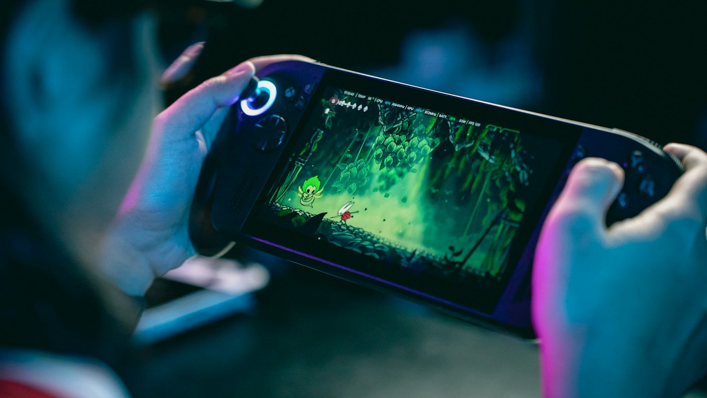 A person holds a handheld console playing a platformer game.